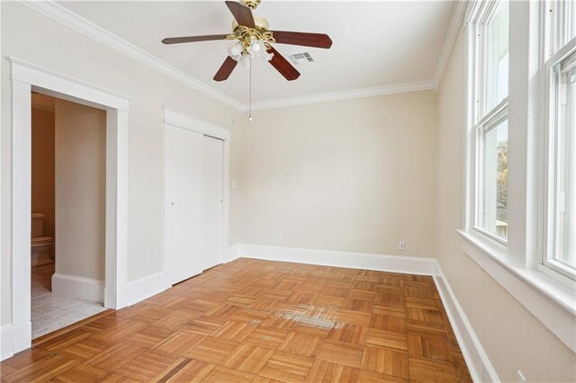 empty room featuring crown molding, a ceiling fan, visible vents, and baseboards