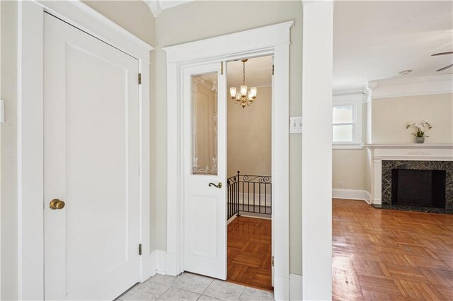 hallway with crown molding, baseboards, and an inviting chandelier