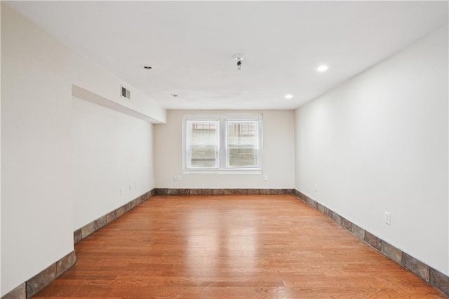 spare room with recessed lighting, wood finished floors, visible vents, and baseboards