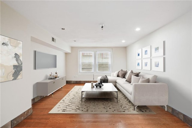 living room with baseboards, visible vents, and wood finished floors