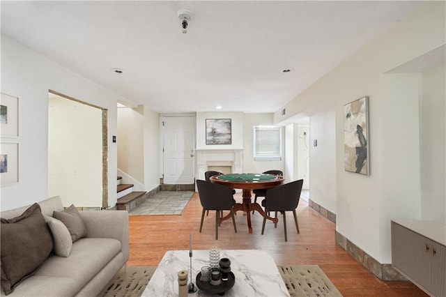 living room featuring light wood-style flooring, a fireplace, stairway, and baseboards