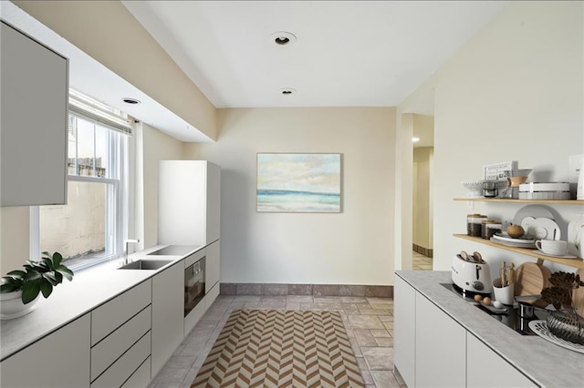 kitchen with modern cabinets, light countertops, a sink, and oven