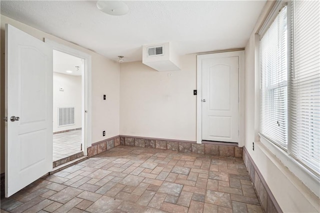 unfurnished room featuring stone finish flooring and visible vents