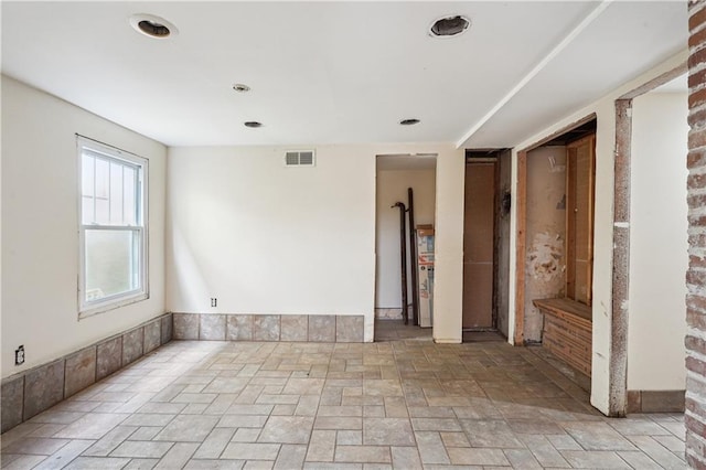 spare room featuring stone finish floor and visible vents