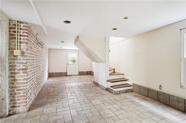 bonus room featuring stairs, brick wall, and baseboards