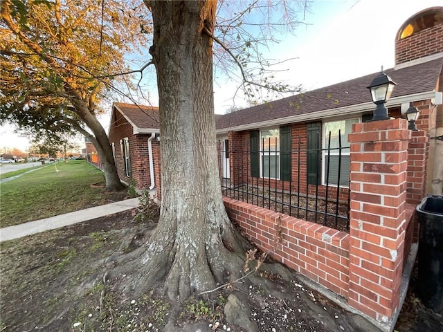 view of property exterior featuring brick siding, a lawn, and a shingled roof