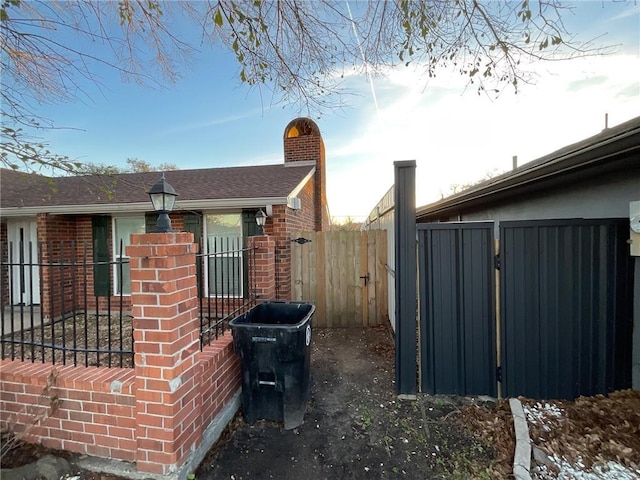 view of side of property with brick siding, fence, a chimney, and roof with shingles