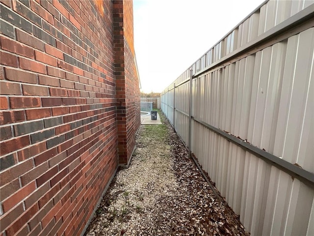 view of side of home with brick siding and fence