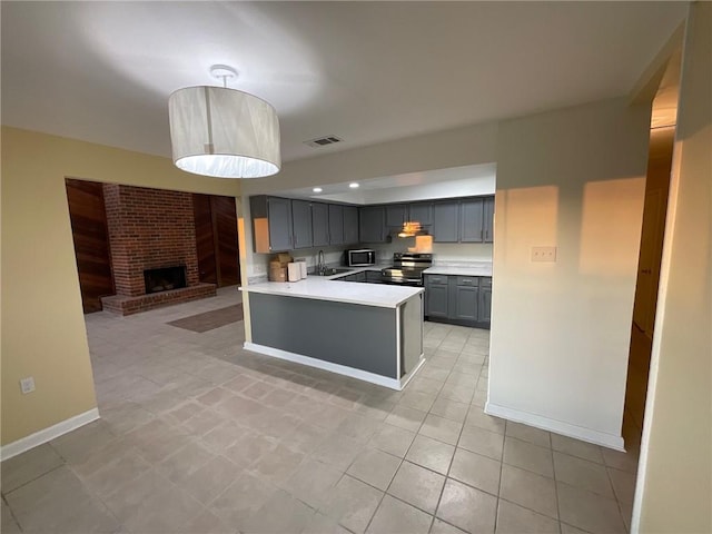 kitchen featuring light countertops, gray cabinetry, appliances with stainless steel finishes, open floor plan, and a sink