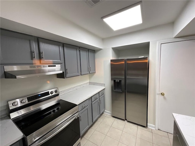 kitchen featuring light tile patterned floors, visible vents, stainless steel appliances, light countertops, and under cabinet range hood