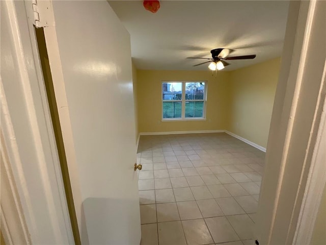 spare room featuring light tile patterned floors, ceiling fan, and baseboards