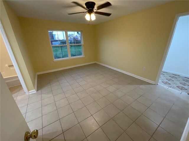 unfurnished room with a ceiling fan, baseboards, and light tile patterned floors