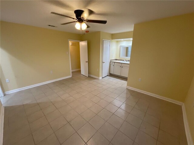 unfurnished bedroom with light tile patterned floors, connected bathroom, a ceiling fan, visible vents, and baseboards