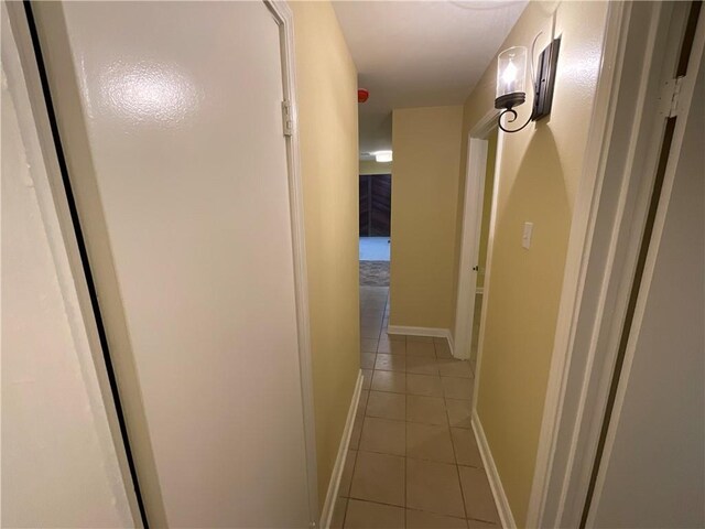 corridor with baseboards and light tile patterned floors