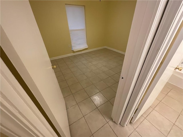 unfurnished room with light tile patterned floors and baseboards