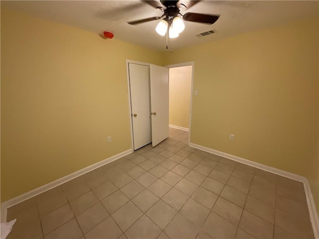 unfurnished room with a ceiling fan, visible vents, baseboards, and light tile patterned floors