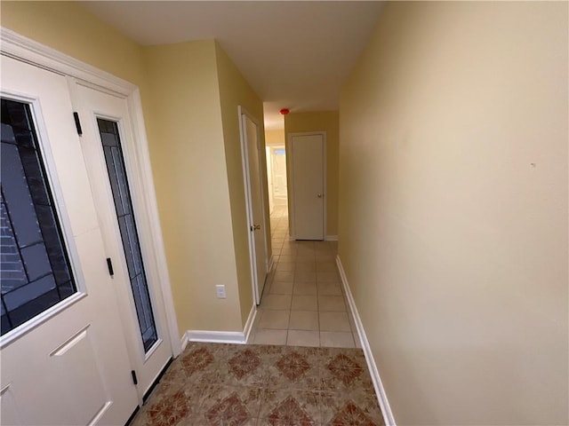 hallway featuring light tile patterned flooring and baseboards