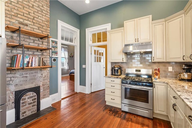 kitchen featuring dark wood-type flooring, stainless steel gas stove, under cabinet range hood, and cream cabinets