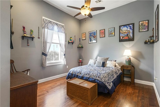 bedroom with ceiling fan, wood finished floors, visible vents, and baseboards