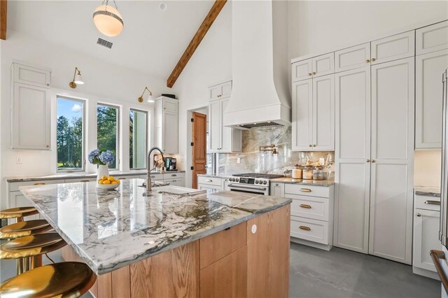 23648 Goodlife Ln, Covington, LA 70435 - kitchen featuring custom range hood, tasteful backsplash, beamed ceiling, high end range, and finished concrete flooring