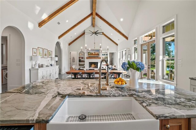 23648 Goodlife Ln, Covington, LA 70435 - kitchen featuring high vaulted ceiling, open floor plan, a lit fireplace, beamed ceiling, and stone counters