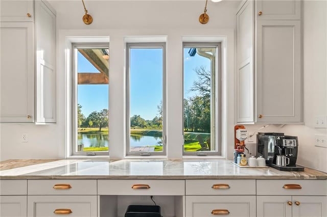 23648 Goodlife Ln, Covington, LA 70435 - kitchen with light stone counters, white cabinetry, and a water view