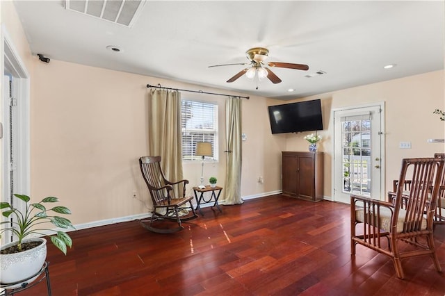 living area with a ceiling fan, hardwood / wood-style flooring, visible vents, and baseboards