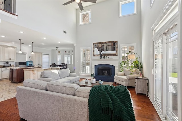 living room with visible vents, ceiling fan, wood finished floors, a brick fireplace, and recessed lighting