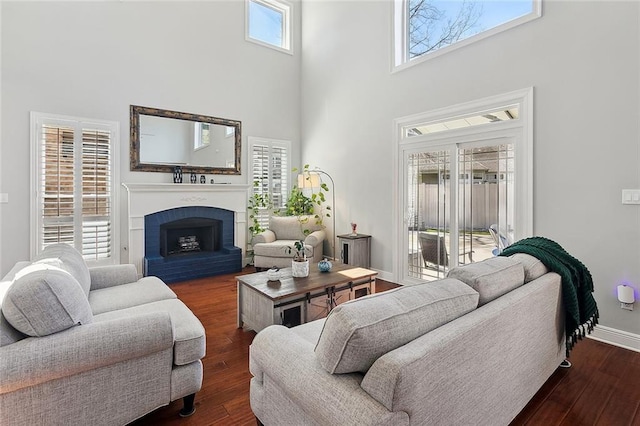 living room with a high ceiling, a fireplace, hardwood / wood-style flooring, and baseboards