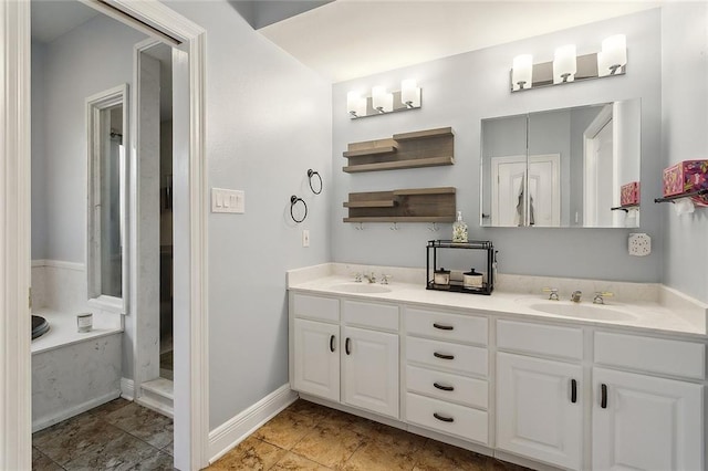 full bath with double vanity, a garden tub, baseboards, and a sink