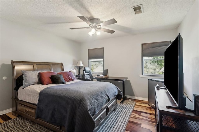 bedroom featuring baseboards, visible vents, multiple windows, and wood finished floors