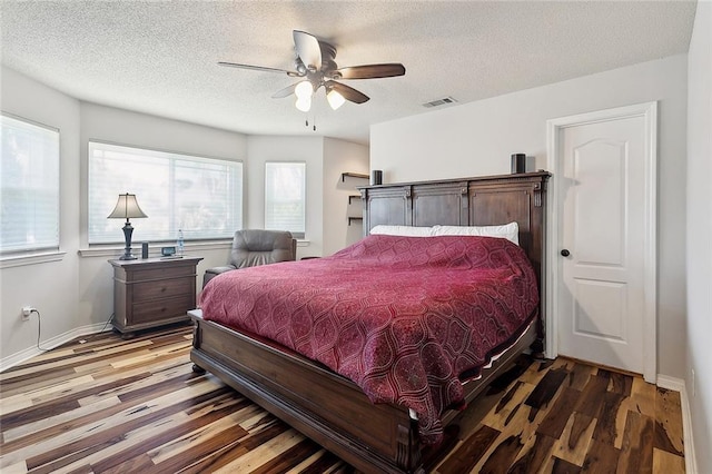 bedroom with baseboards, visible vents, ceiling fan, wood finished floors, and a textured ceiling