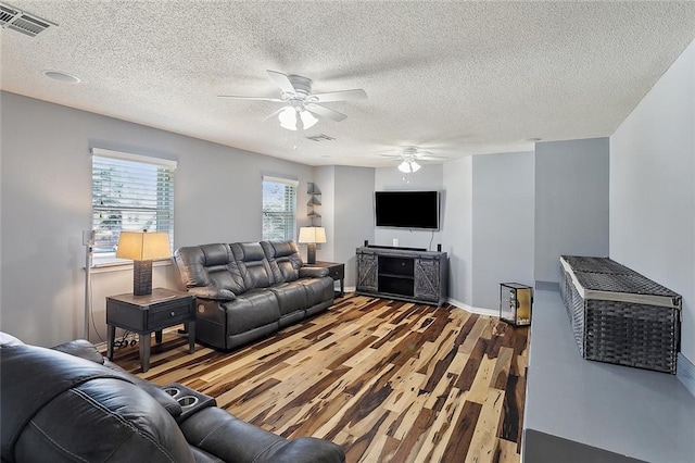 living room featuring a ceiling fan, baseboards, visible vents, and wood finished floors