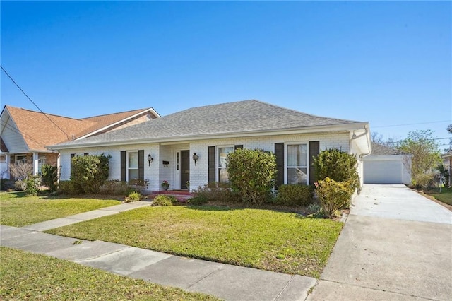 view of front of home with an outbuilding, brick siding, a front yard, and a garage