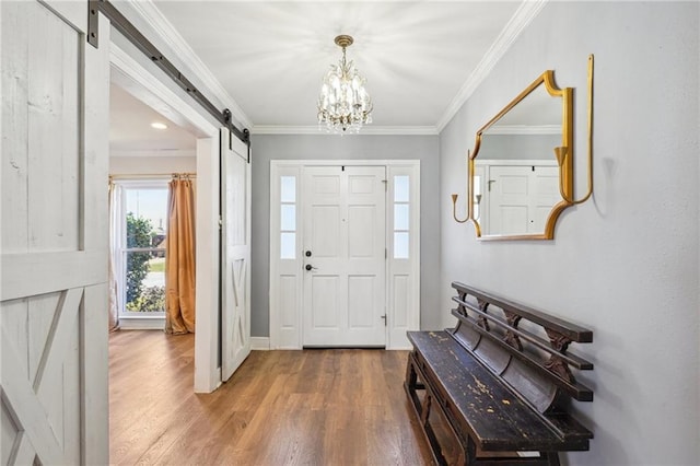 foyer featuring an inviting chandelier, a barn door, ornamental molding, and wood finished floors