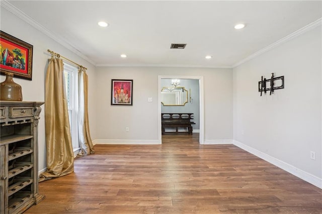 spare room featuring baseboards, wood finished floors, and crown molding