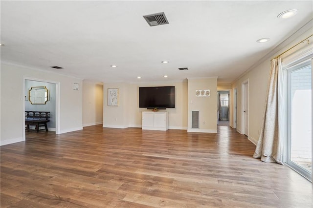 unfurnished living room with a wealth of natural light, ornamental molding, wood finished floors, and visible vents