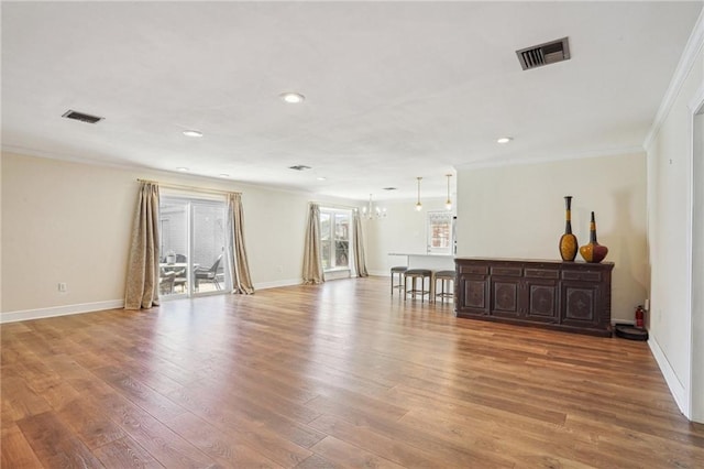 empty room with light wood-style floors, baseboards, visible vents, and ornamental molding