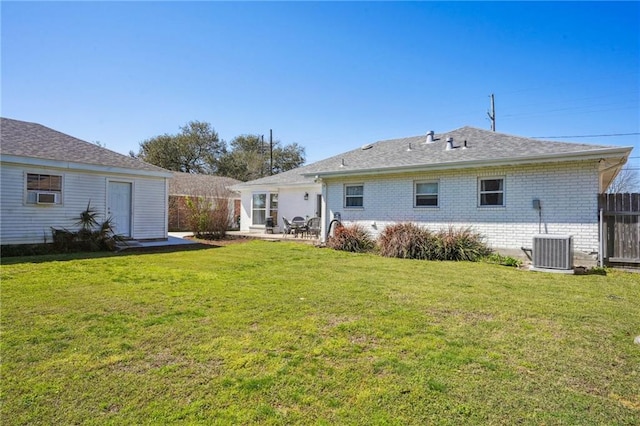 rear view of house featuring cooling unit, brick siding, fence, a lawn, and a patio area