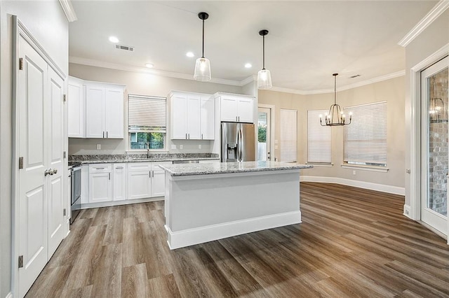 kitchen with range, a kitchen island, ornamental molding, and stainless steel fridge with ice dispenser