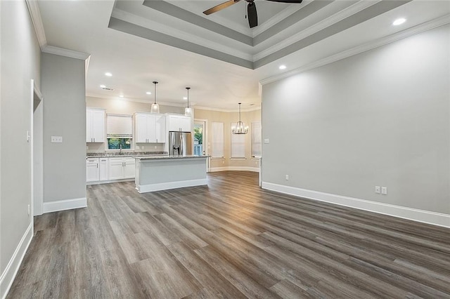 kitchen featuring ceiling fan with notable chandelier, a kitchen island, open floor plan, white cabinetry, and stainless steel fridge with ice dispenser