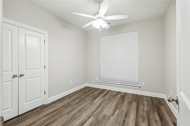 unfurnished room with baseboards, a ceiling fan, and dark wood-style flooring