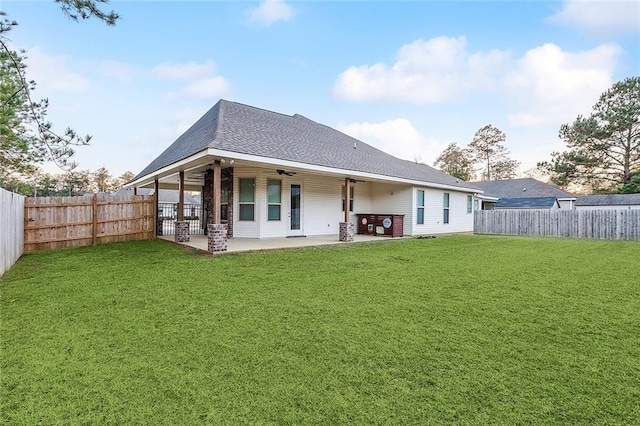 back of house featuring a shingled roof, ceiling fan, a fenced backyard, a yard, and a patio