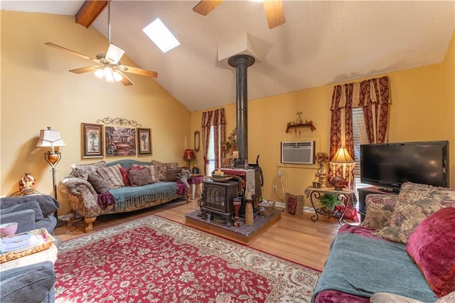 living area with vaulted ceiling with beams, ceiling fan, wood finished floors, a wall mounted AC, and a wood stove