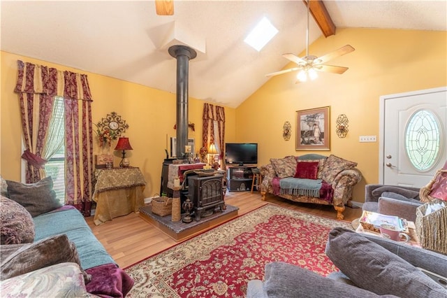 living area with lofted ceiling with beams, plenty of natural light, wood finished floors, and a wood stove