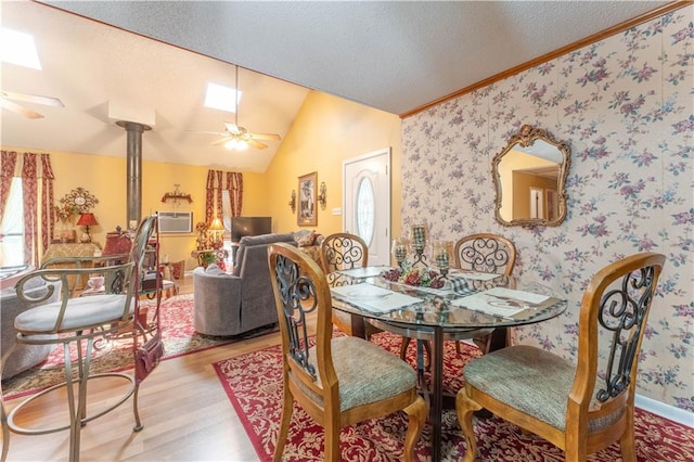 dining room featuring lofted ceiling, a textured ceiling, wood finished floors, and wallpapered walls