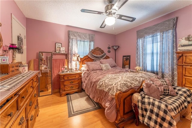 bedroom featuring ceiling fan, light wood-style flooring, and a textured ceiling