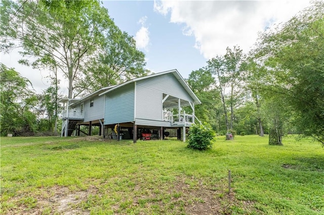 back of house featuring a carport, stairway, and a lawn