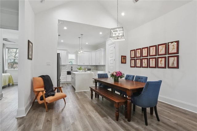 dining room featuring high vaulted ceiling, recessed lighting, wood finished floors, and baseboards