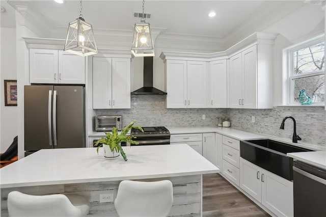 kitchen with stainless steel appliances, a sink, visible vents, ornamental molding, and wall chimney exhaust hood